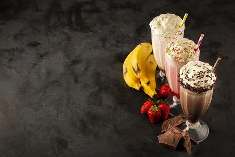 Three glasses of milkshake with assorted flavors. Chocolate, vanilla and st.. Stock Photos