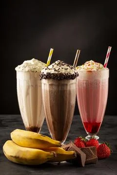 Three glasses of milkshake with assorted flavors. Chocolate, vanilla and st.. Stock Photos