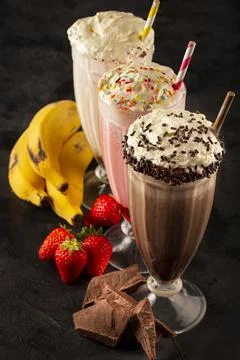 Three glasses of milkshake with assorted flavors. Chocolate, vanilla and st.. Stock Photos
