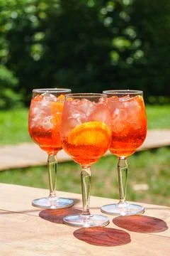 Three glasses or refreshing orange spritz cocktails with ice and citrus sli.. Фото