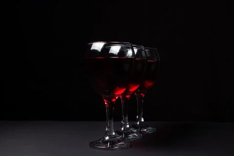 Three glasses of red wine on a black background. Stock Photos