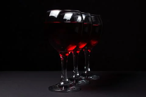 Three glasses of red wine on a black background. Stock Photos