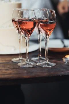 Three glasses of rose wine rest on a dark wooden table Foto stock