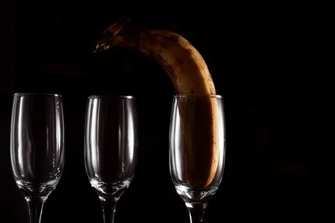 Three glasses of wine on a dark background with a banana. Conceptual photo Stock Photos