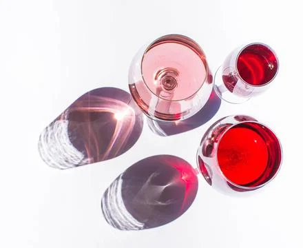 Three glasses of wine: red and pink on white background with sparkling shadow Stock Photos