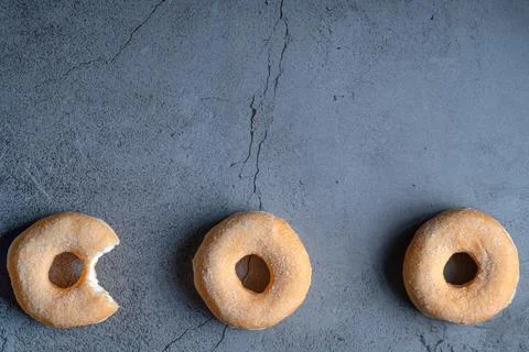 Three glazed donuts lined up on concrete background with copy space Fotos de archivo