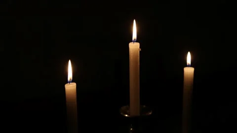 Three glowing candles burning in the dark, creating a serene and tranquil atmosp Stock Footage 293496435