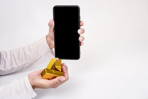 Three gold bars and a mobile phone with a black screen are being held again.. Stock Photos