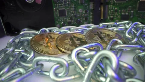Three gold Bitcoin surrounded by silver chain and Hadr Drive disk rotate on the Stock Footage 141377516