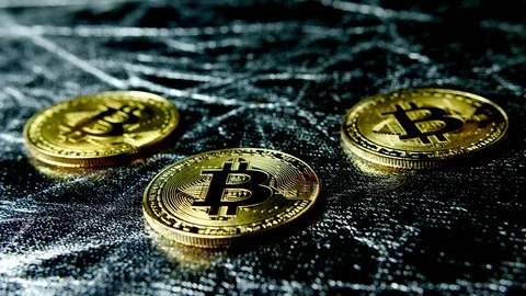 Three gold BTC cryptocurrency coins on silver surface, bit coin currency crypto Stock Footage 85686250
