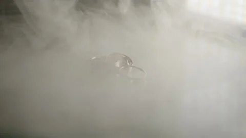 Three gold wedding rings on a reflective surface with smoke. slow motion. Stock Footage 314979330