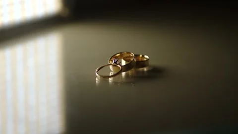 Three gold wedding rings on a reflective surface with smoke. slow motion. Stock Footage 314979335