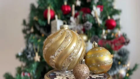 Three golden baubles rotating with blurred tree Stock Footage 341611403