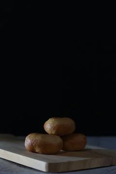 Three Golden-Brown Fried Bread on Wooden Board, Dark Background Stock Photos
