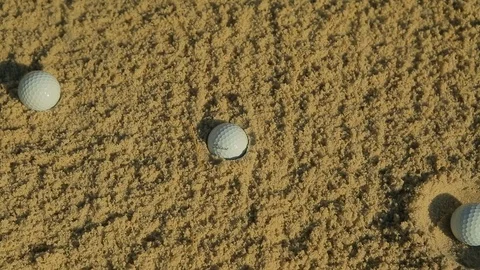 Three golf balls sitting in sand pit on golfing course B Stock Footage 125331996