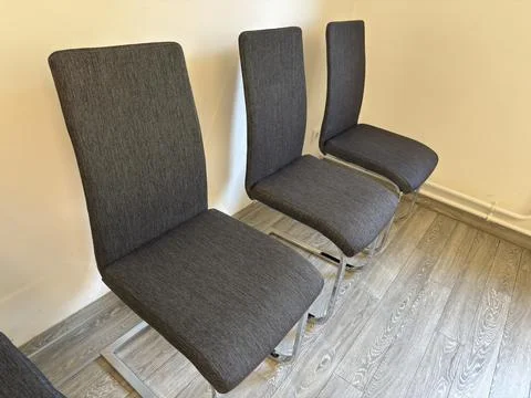 Three gray chairs with circular thread patterns and metal legs Foto stock