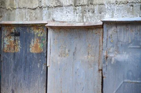 Three gray rusty trash bins on a cloudy day. Stock Photos