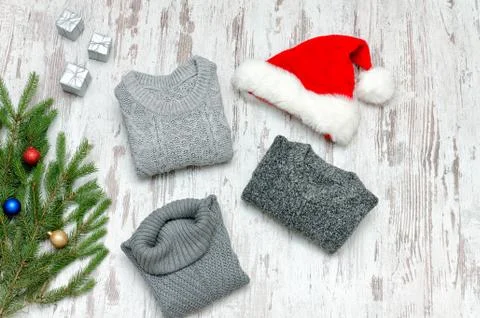Three gray sweaters, Santa's hat and fir branch on a wooden background. Fashi Stockfoto's