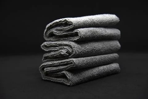 Three gray towels on a black background. Terry cloths for wiping furniture... Stock Photos