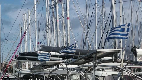 Three Greek flags, and one French, blowing in the wind at a yacht harbour Stock Footage 144679924