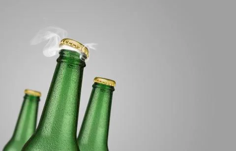 Three green beer bottles on grey background Photos