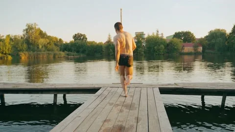 Three guys jump from a tree pier into a lake. Stock Footage 213207442