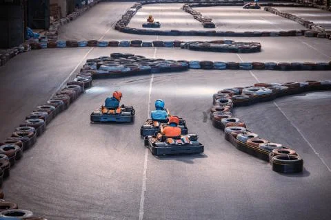 Three guys overtaking each other on an indoor karting track Stock Photos