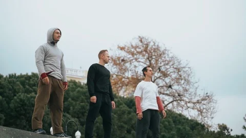 Three guys stand on the parapet after parkour training. The guy is training Stock Footage 120423701