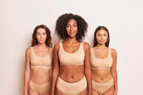 Three half-naked girls of different races stand in the studio dressed only in Stock Photos