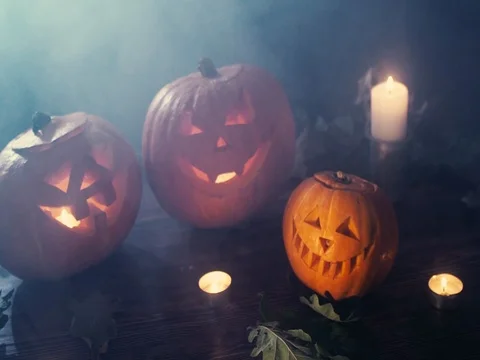 Three Halloween pumpkins head jack lantern with burning candles over black Stock Footage 80245416
