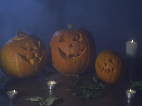 Three Halloween pumpkins head jack lantern with burning candles over black Video stock 80245670