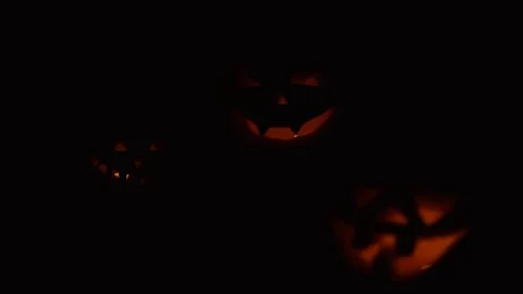 Three Halloween pumpkins head jack lantern with burning candles over black Video stock 80246653