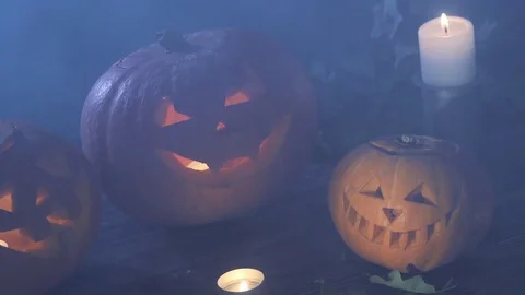 Three Halloween pumpkins head jack lantern with burning candles over black Stock Footage 80247357