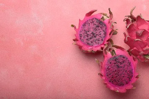 Three halves of dragon fruit lying on pink background top view with copy space Foto stock