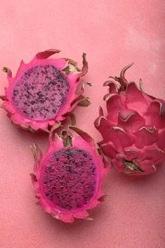 Three halves of dragon fruit lying on pink background top view Foto stock