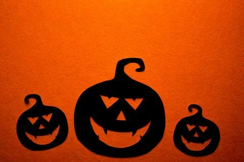 Three hand-painted black pumpkins on an orange background Stock Photos
