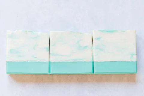 Three handmade soap bars with teal and white marbled design Stock Photos