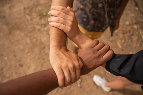 Three hands of different ethnicities grasp each other and form a triangle Foto stock