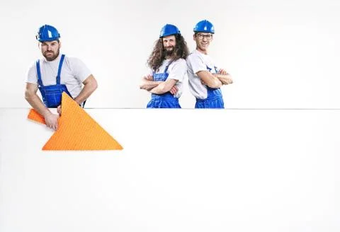Three handsome craftsmen posing next to the empty white board Фото
