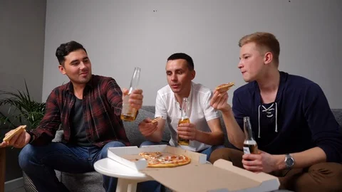Three handsome young friends ating pizza taking it from table. Stock Footage 118847855