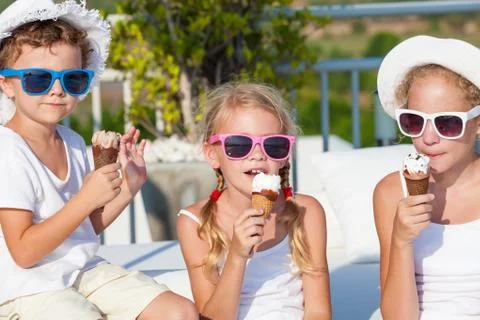 Three happy children eating ice cream near swimming pool at the day time. Fotos de archivo