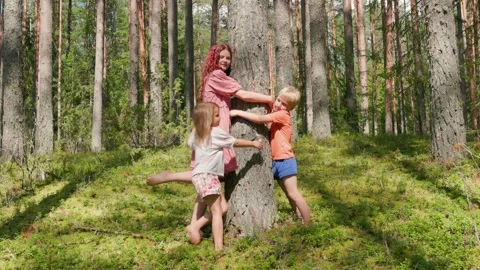 Three happy children hugging a tree together in a lush summer forest settin.. Stock Footage 317677073