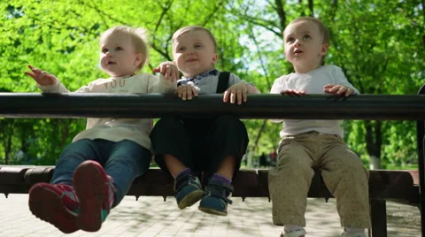 Three happy children sitting on a bench in the park Stock Footage 62802570