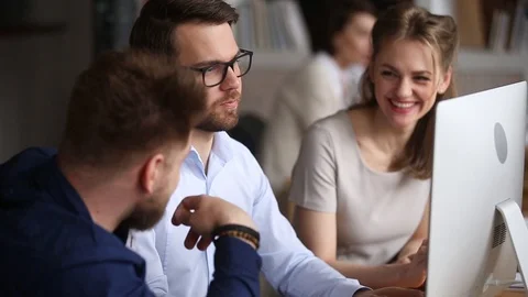 Three happy colleagues working together discussing computer project in teamwork Stock Footage 107162947