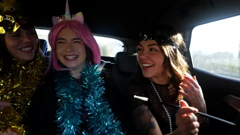 Three happy friends singing and dancing in a car during a costume party Stock Footage 324465864