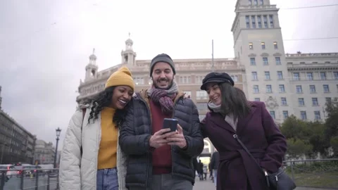 Three happy friends walking in a city using smartphone content in winter in the Stock Footage 211893533