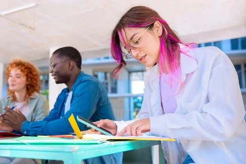 Three happy multiracial students studying with smartphones outdoors. Stock Photos