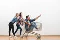 The three happy people fun with a shopping cart on a white wall background Photo