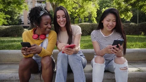 Three happy women using cell phone outdoors. Classmates having fun watching Stock Footage 234659886