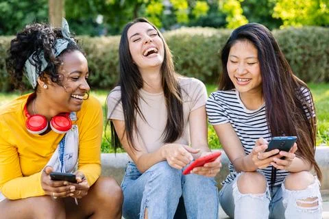 Three happy women using mobile phones at city street Stock Photos